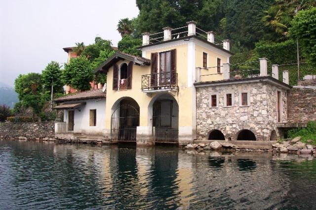 a house sitting on the water next to a lake at boat house facing the lake in Orta San Giulio