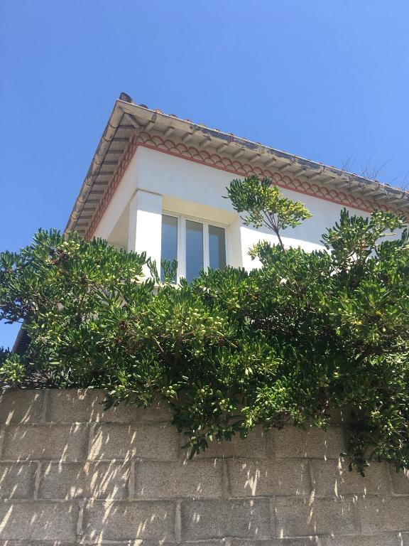 une maison blanche avec des buissons sur un mur dans l'établissement Dans une maison, appartement indépendant et jardin, à Perpignan