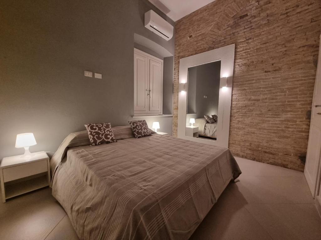 - une chambre avec un grand lit et un mur en briques dans l'établissement Luxury Apple Room Apartment Cagliari, à Cagliari