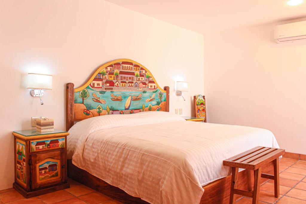 オアハカにあるCasa Rosa Mexicanoのベッドルーム1室(大型ベッド1台、木製ヘッドボード付)