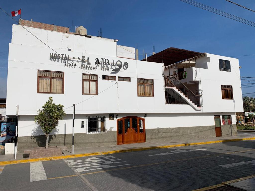 a white building on the corner of a street at Hostal El Amigo in Paracas