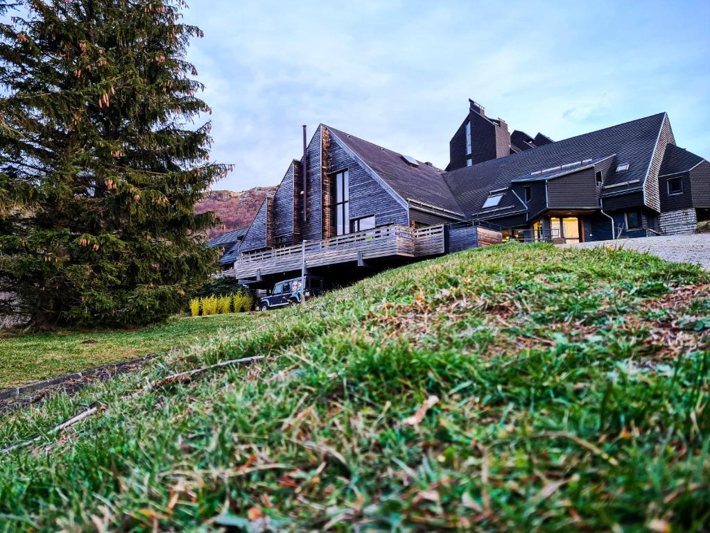 ein großes Haus auf einem Hügel mit einem Baum in der Unterkunft Sancy Resort in Chambon-sur-Lac