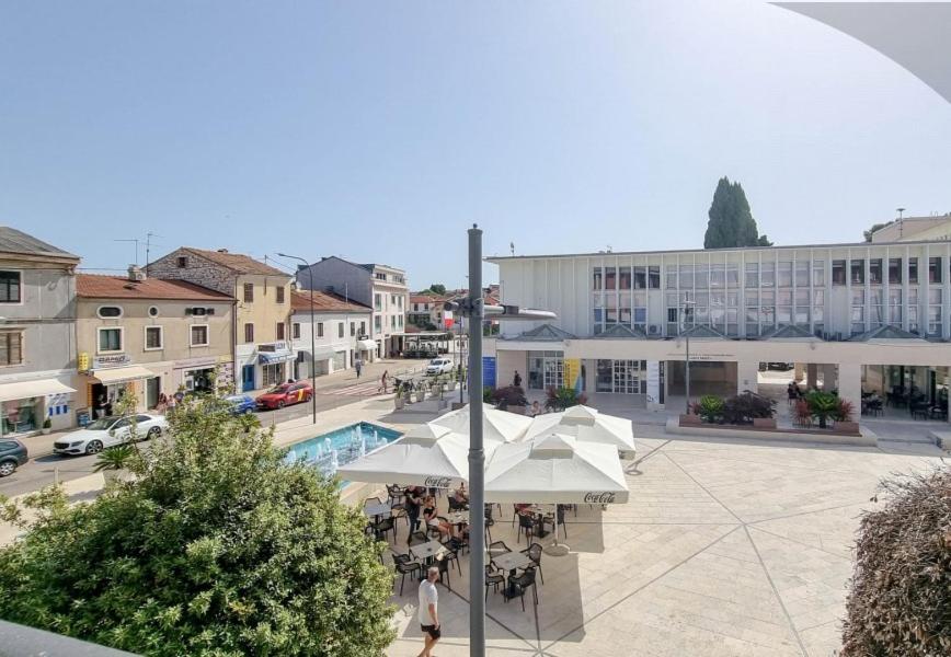 a view of a town with a courtyard with tables and umbrellas at Bella Apartment in Umag