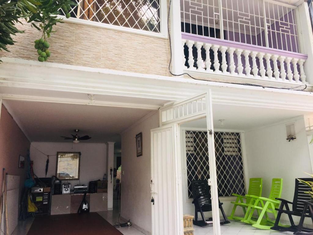 un balcón en una casa con sillas verdes en Casa Feliz Hostal, en Santa Marta