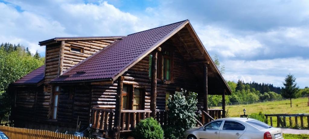 una cabaña de madera con un coche aparcado delante de él en Cabana Belis Dealu Negru, en Beliş