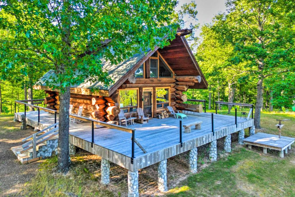 une cabane en rondins dans les bois avec une grande terrasse dans l'établissement Rustic Hideaway Fire Pits, Grills, 87 Acres!, 