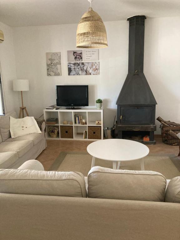 sala de estar con sofá, mesa y chimenea en Casa rural La Hontanilla, en Miguel Esteban