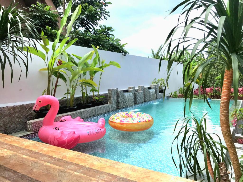a swimming pool with two pink flamingos in the water at THE OASIS 4BR Private Pool Pet-Friendly Villa Vimala Hills in Gadok 1