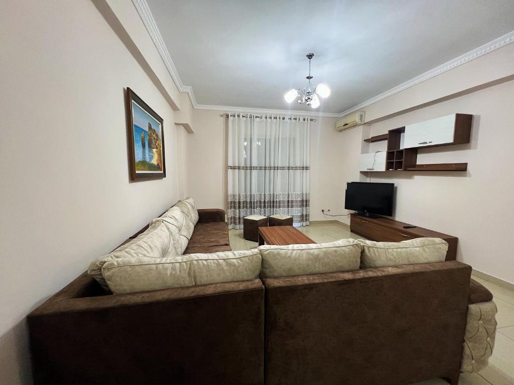 ein Wohnzimmer mit einem großen Sofa und einem TV in der Unterkunft Silvi C&S in Fier