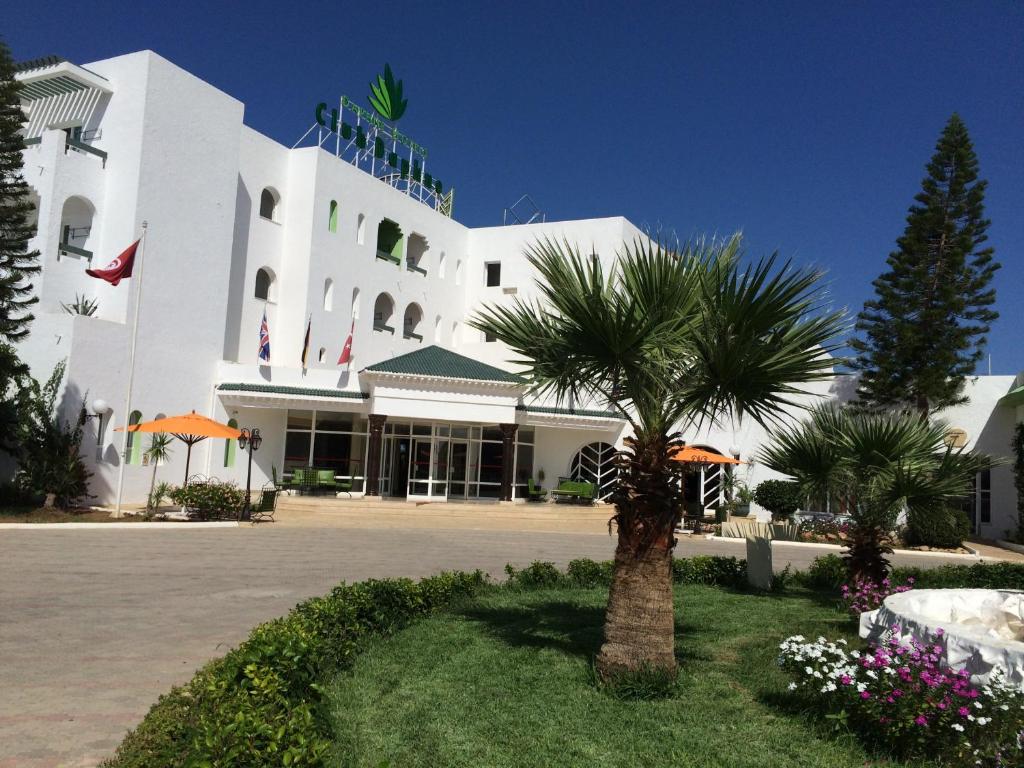 a white building with a palm tree in front of it at Miramar Sharm El Kantaoui in Port El Kantaoui