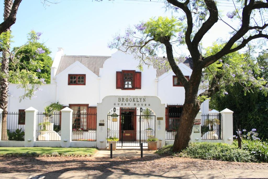 a white house with a tree in front of it at Brooklyn Guesthouses in Pretoria