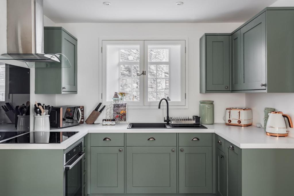 uma cozinha com armários verdes e um lavatório em Pickle Pot Loft- 2 bedroom apartment in Hawkshead em Hawkshead