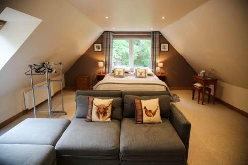 een slaapkamer met een bank en een bed op zolder bij Riverside Loft in Barcaldine