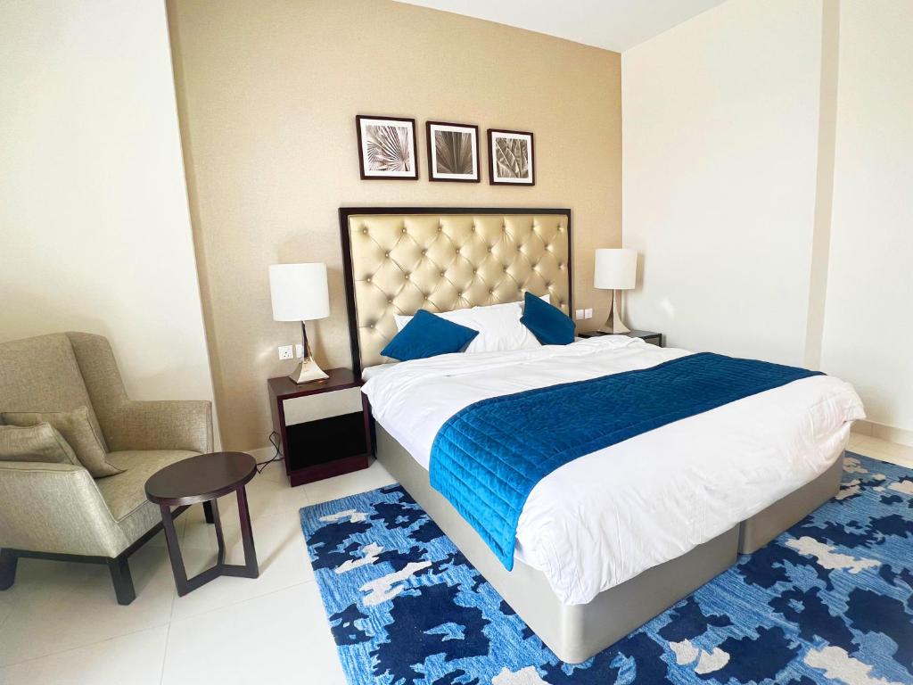 a bedroom with a large bed and a chair at Lovely one bedroom apartment with world class hotel amenities in Dubai