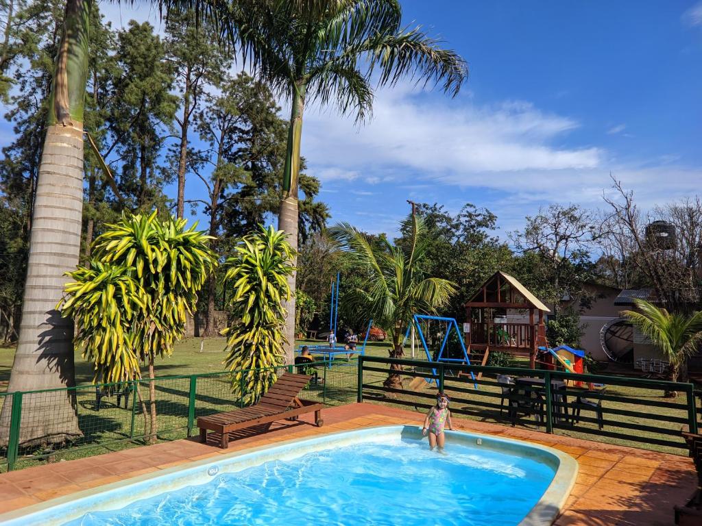 una persona parada en una piscina con un parque infantil en El Rosedal Cataratas en Puerto Iguazú