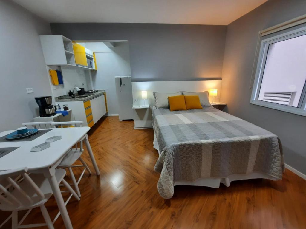 a bedroom with a bed and a table and a kitchen at Descanse em Lindo Studio na Bela Vista em São Paulo in Sao Paulo