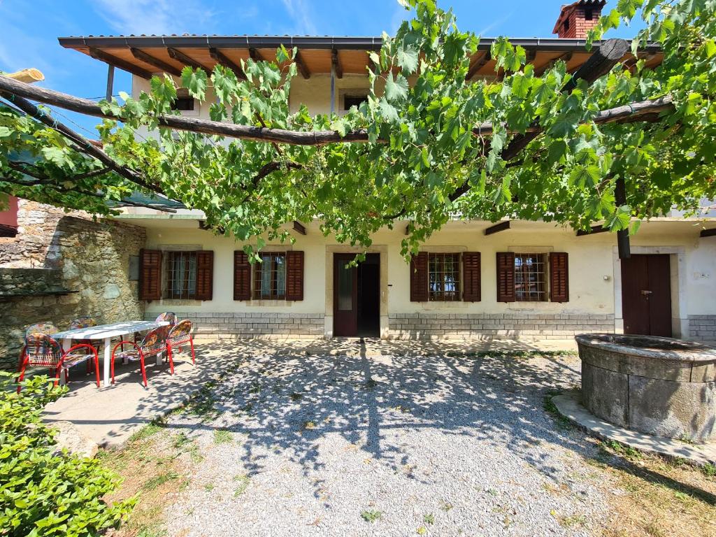 uma casa com uma mesa e cadeiras em frente em Luketovi em Kostanjevica na Krasu