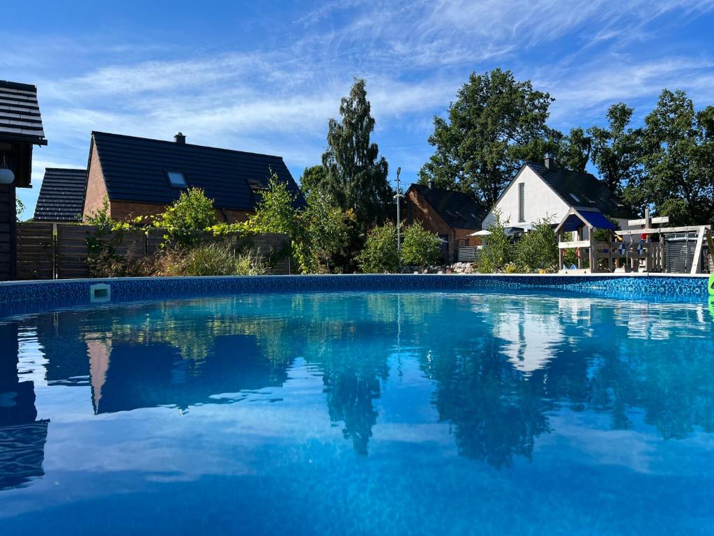 une grande piscine d'eau bleue avec des maisons en arrière-plan dans l'établissement Ulinia Zacisze Dom Superior 90m2, à Ulinia