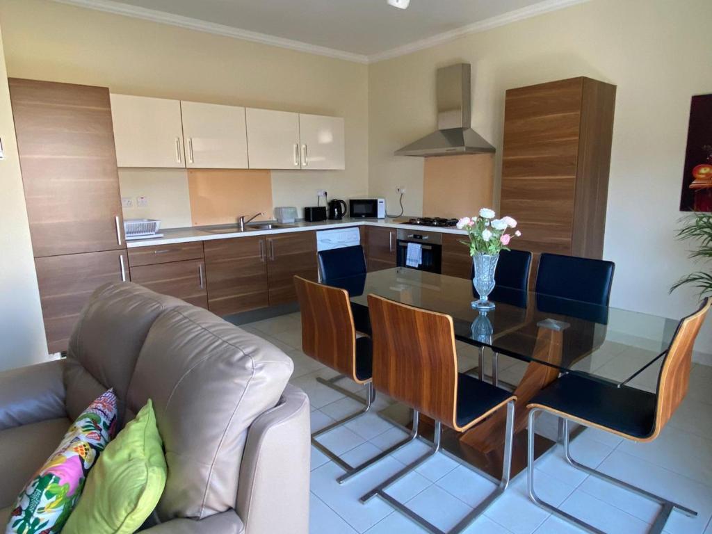 uma sala de estar com uma mesa de vidro e um sofá em Newly Refurbished Mellieha Central apartment em Mellieħa