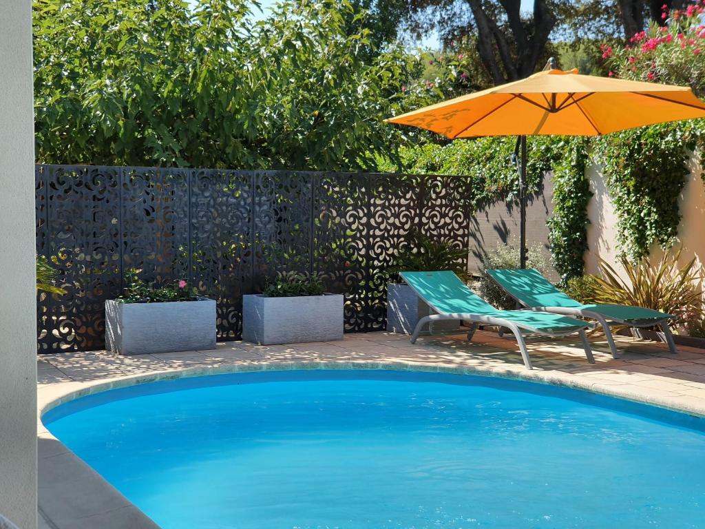 een zwembad met een parasol en twee stoelen en een tafel bij Gîte " La Petite Compsoise " in Comps