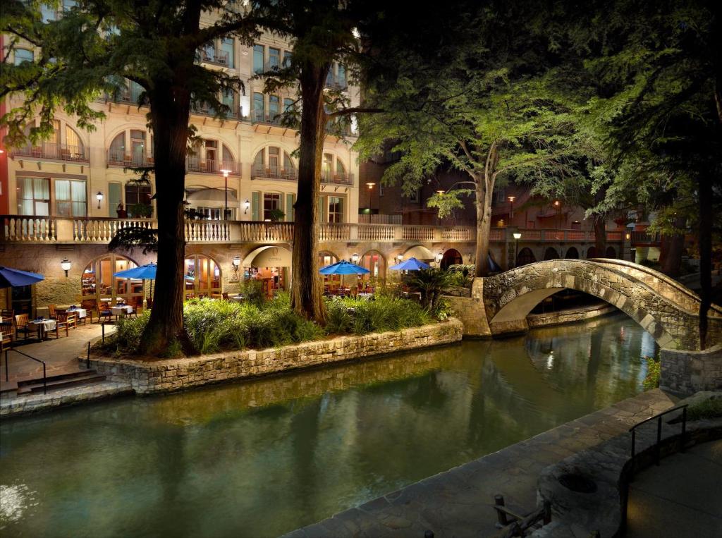 uma ponte sobre um rio em frente a um edifício em Mokara Hotel & Spa em San Antonio