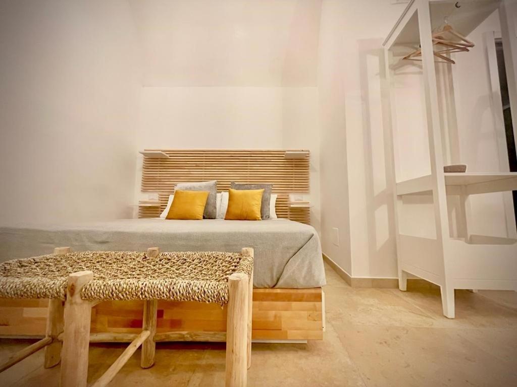 una camera da letto con letto, cuscini gialli e panca di Casa di zia Pupetta a Bari