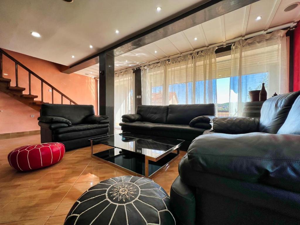 uma sala de estar com sofás pretos e uma mesa em Chalet Snow Valley - Private Pool em Imouzzer Kandar