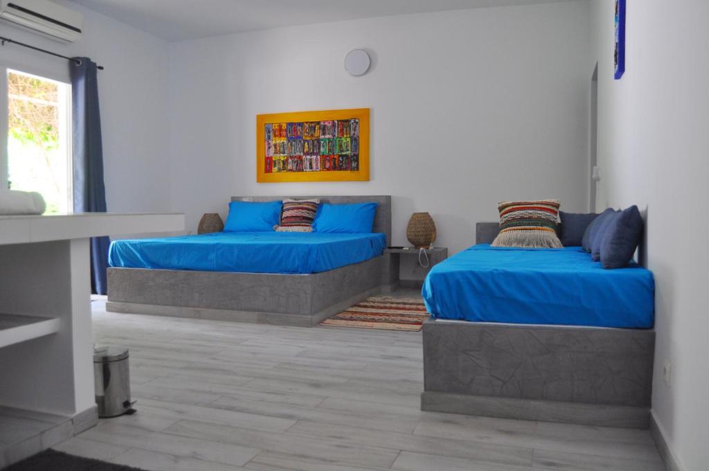 2 camas en una habitación con sábanas y almohadas azules en Keur de Pierre en Saly Portudal