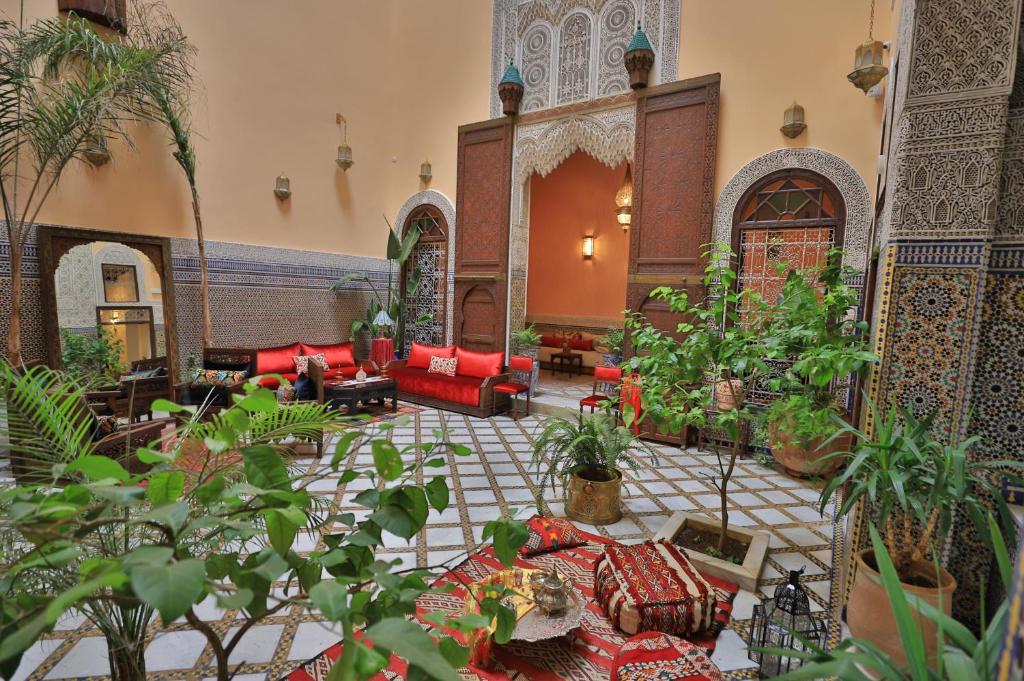 un salon avec des canapés rouges et des plantes dans l'établissement Riad Moulaydriss et Giacomo, à Fès