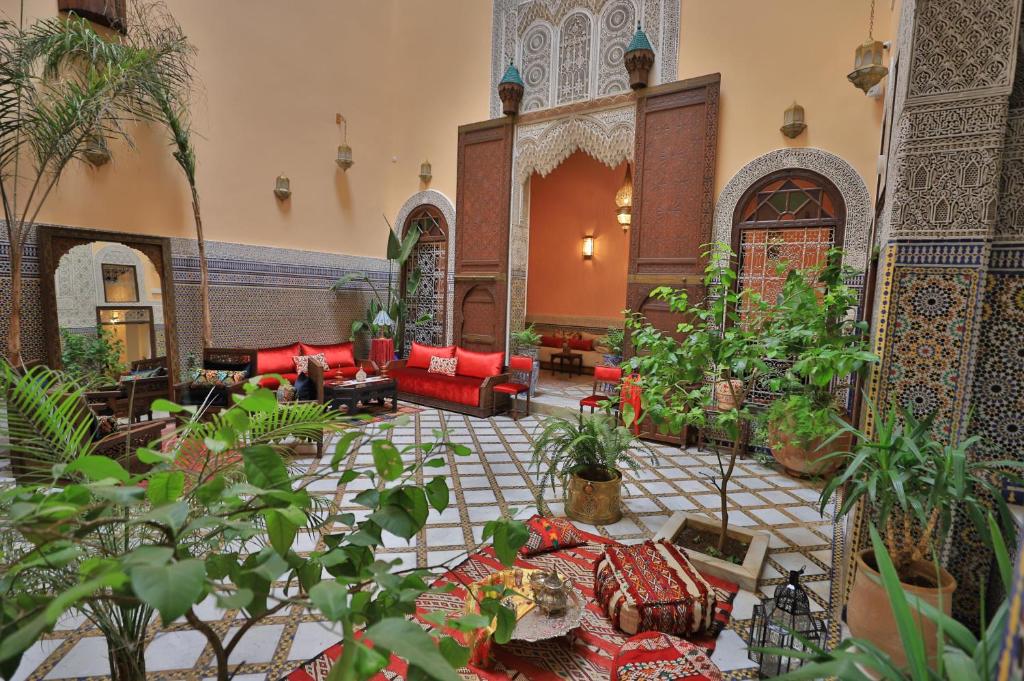 a living room with red couches and plants at Riad Moulaydriss et Giacomo in Fès
