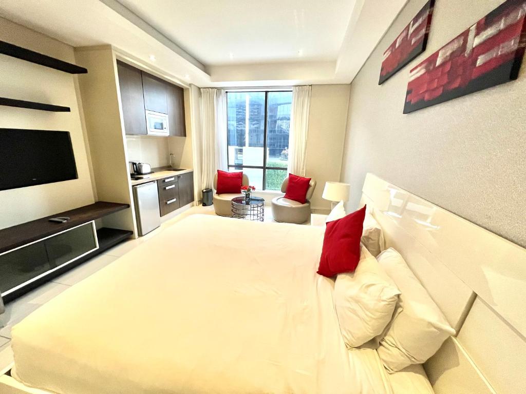 a bedroom with a large white bed with red pillows at A cozy apartment at Sandton Skye in Johannesburg