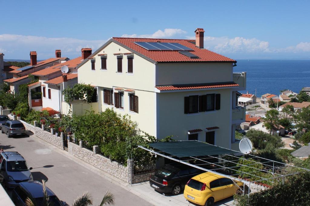 une maison blanche avec des panneaux solaires sur le toit dans l'établissement Apartment Mali Losinj 7879d, à Mali Lošinj