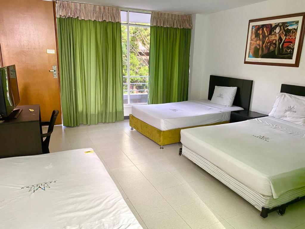 een hotelkamer met 2 bedden en groene gordijnen bij Hotel Santelmo in Cali