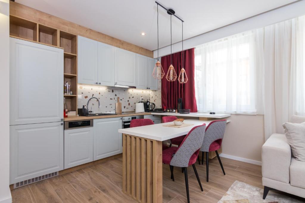 a kitchen with white cabinets and a table and chairs at Mayisa Apartments in Sarajevo