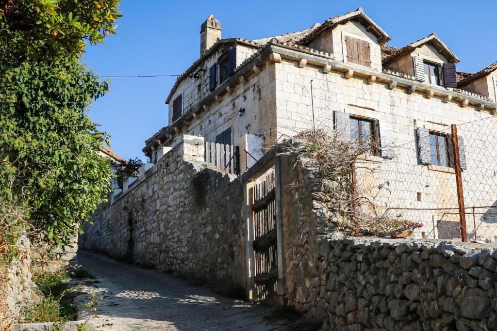 an old stone house with a gate and a stone wall at Holiday house with a parking space Bobovisca, Brac - 11435 in Ložišće