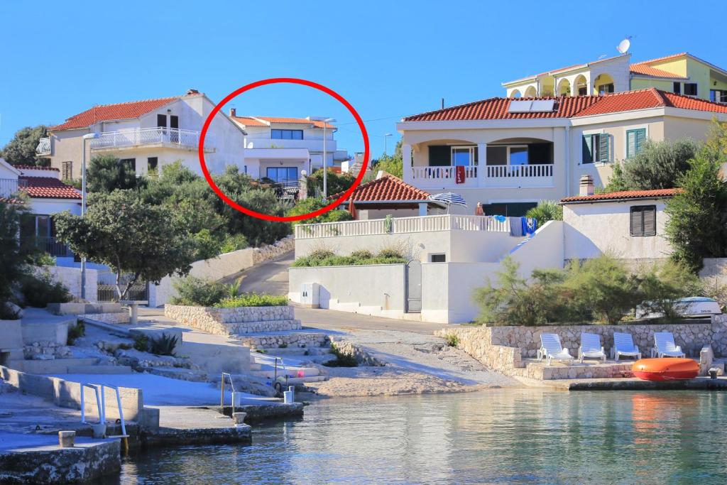 a red circle in front of some houses by the water at Apartments by the sea Cove Ostricka luka, Rogoznica - 11451 in Zaglavice