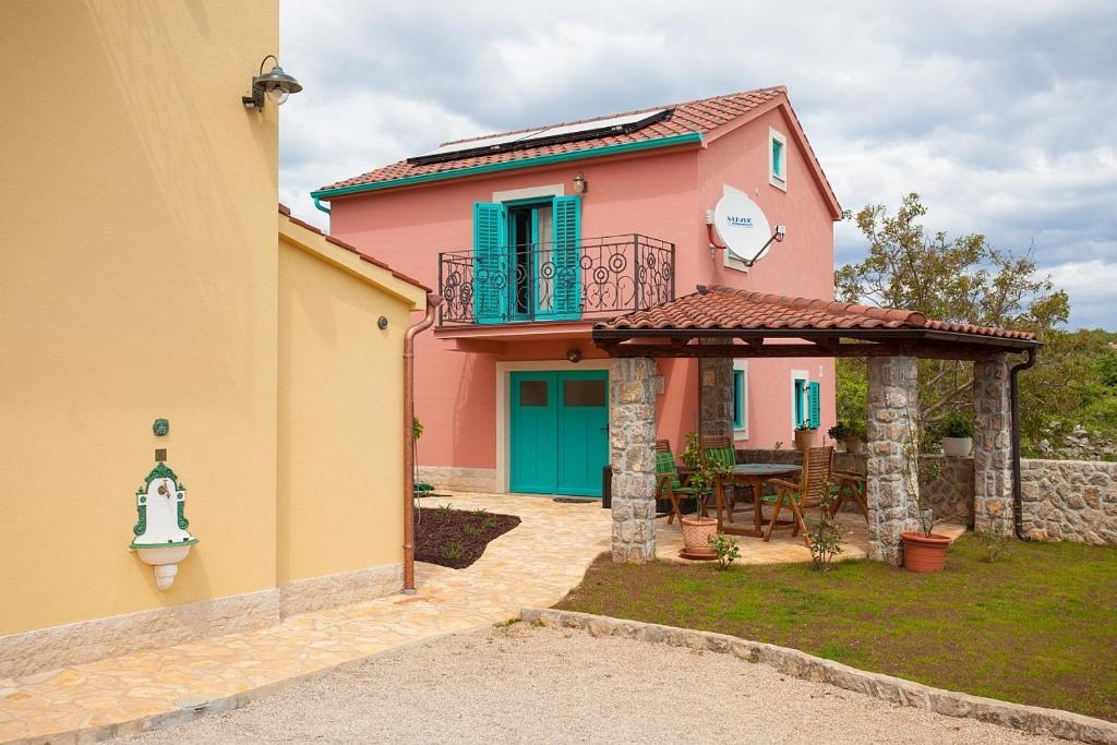 a pink house with a balcony and a table at Holiday house with a parking space Kornic, Krk - 11504 in Kornić