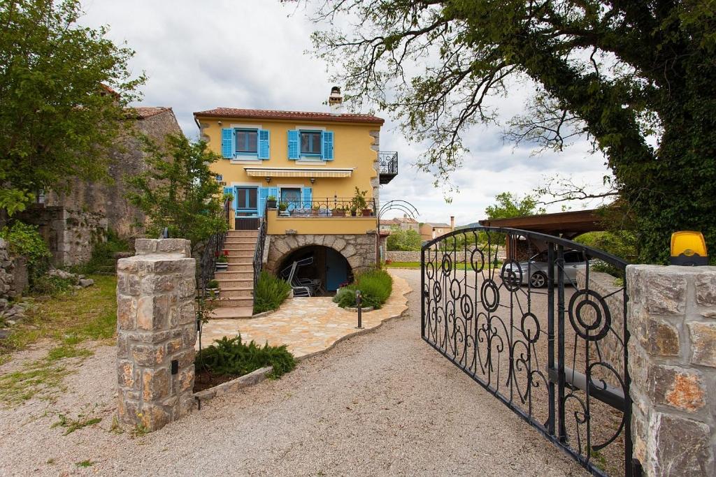 a yellow house with blue windows and a gate at Apartments with a parking space Kornic, Krk - 11506 in Kornić