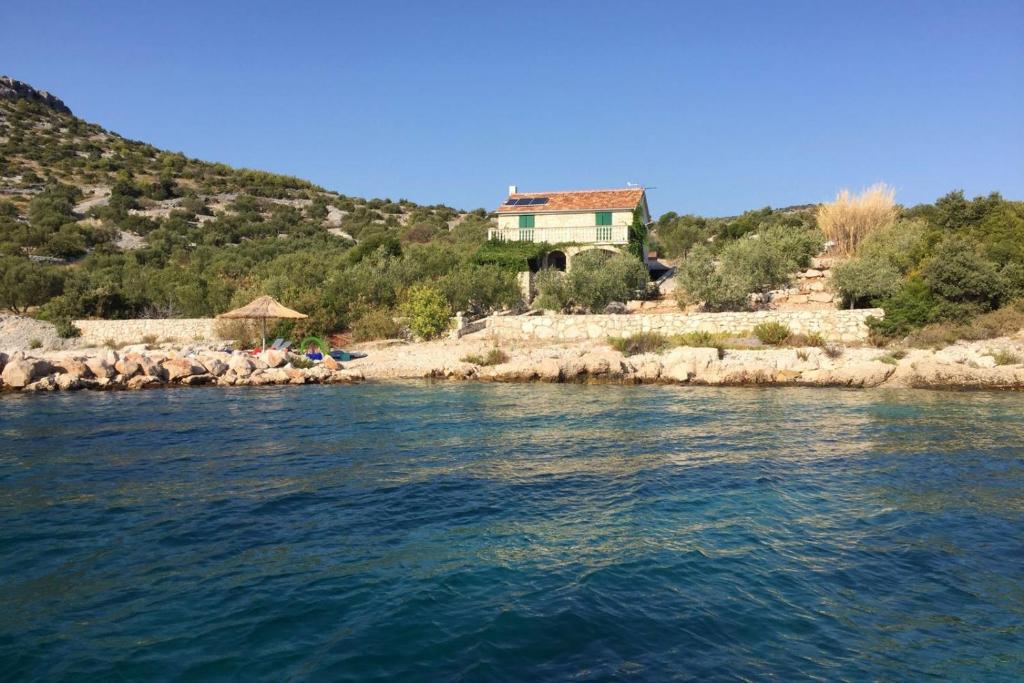 a house on the shore of a body of water at Secluded fisherman's cottage Cove Donje More, Pasman - 11515 in Tkon