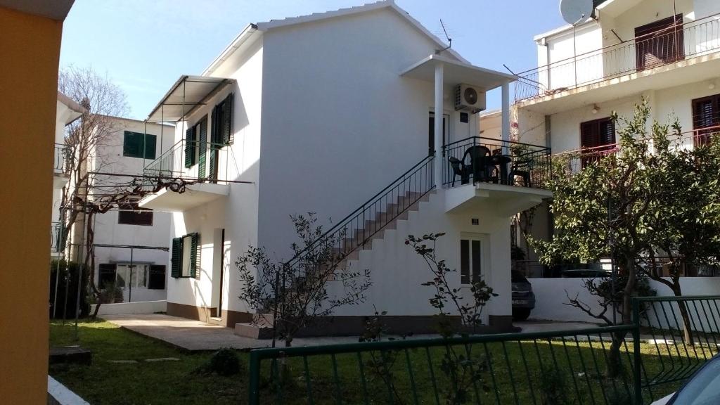 a white building with two people sitting on a balcony at Apartments by the sea Drvenik Donja vala, Makarska - 11553 in Drvenik