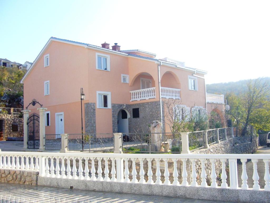 uma grande casa rosa com uma cerca branca em Apartments with a parking space Klenovica, Novi Vinodolski - 11559 em Klenovica