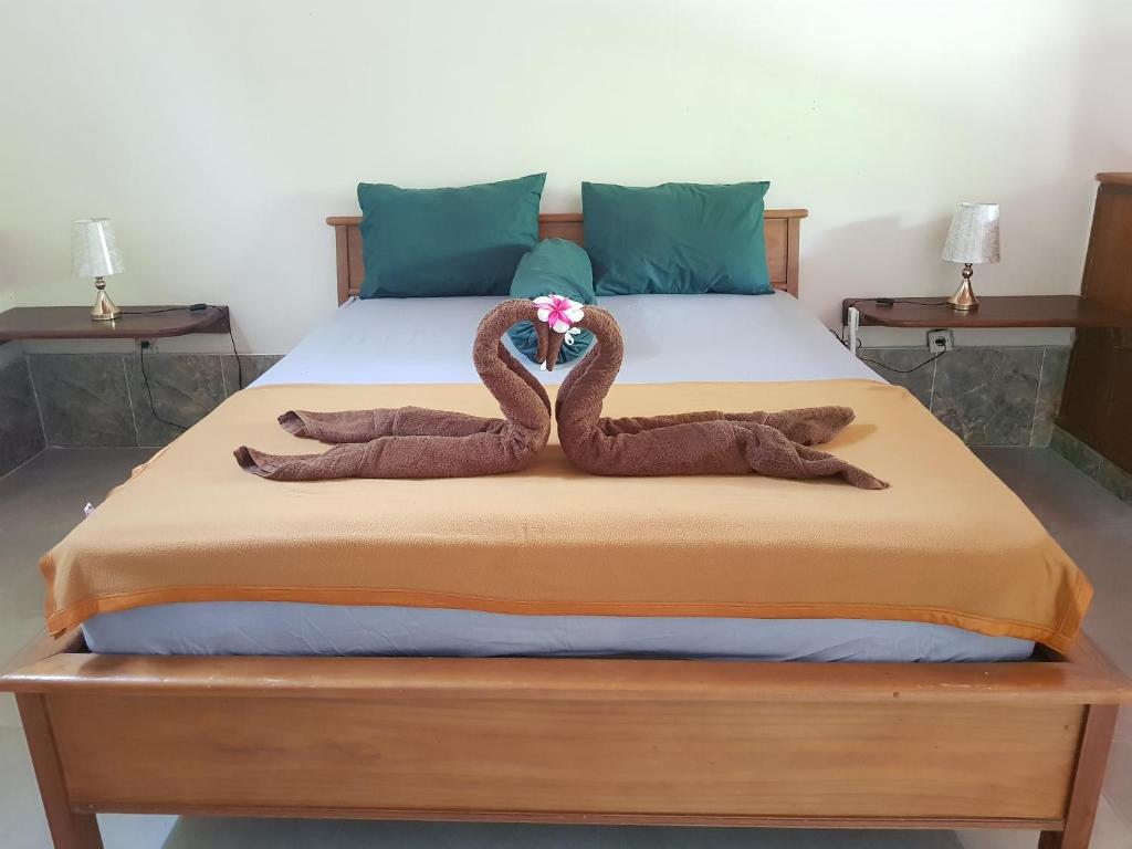 Dos cisnes con toallas sentados en la parte superior de una cama en Run Gilis, en Gili Meno