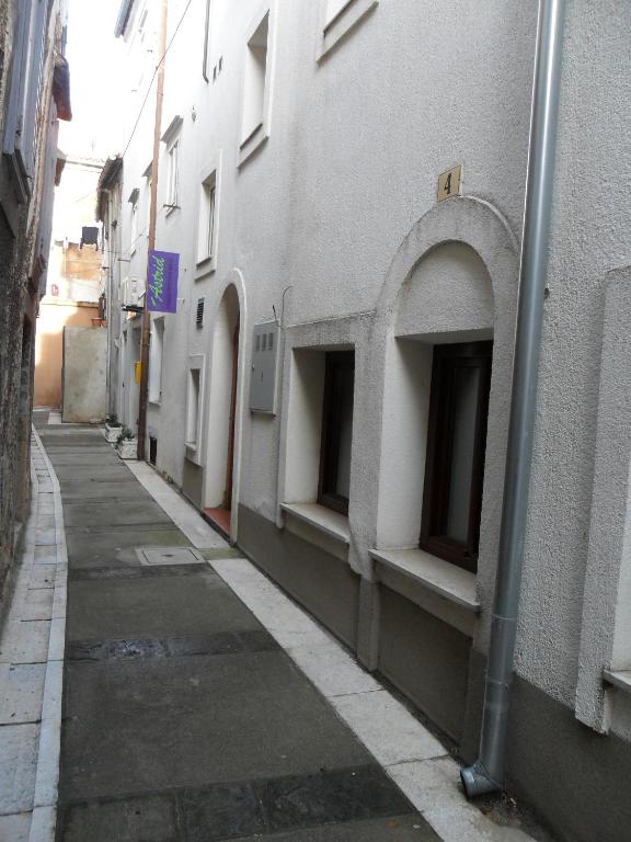 an alley with a building with windows on the side at Apartments by the sea Senj - 11606 in Senj