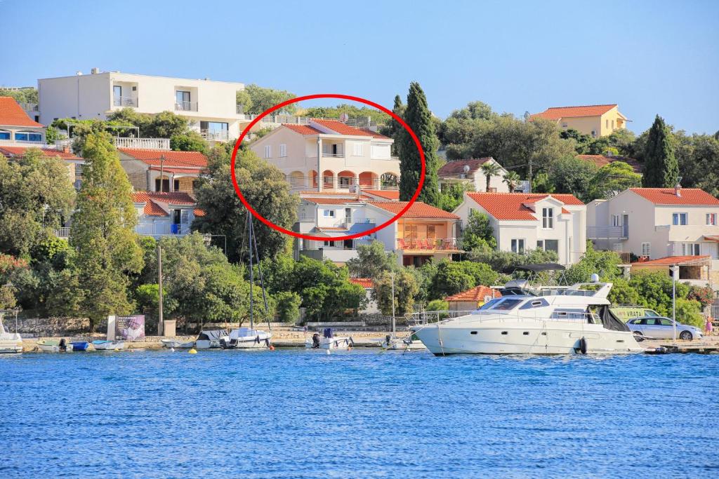 um barco na água em frente a uma casa em Apartments by the sea Seget Vranjica, Trogir - 13771 em Trogir
