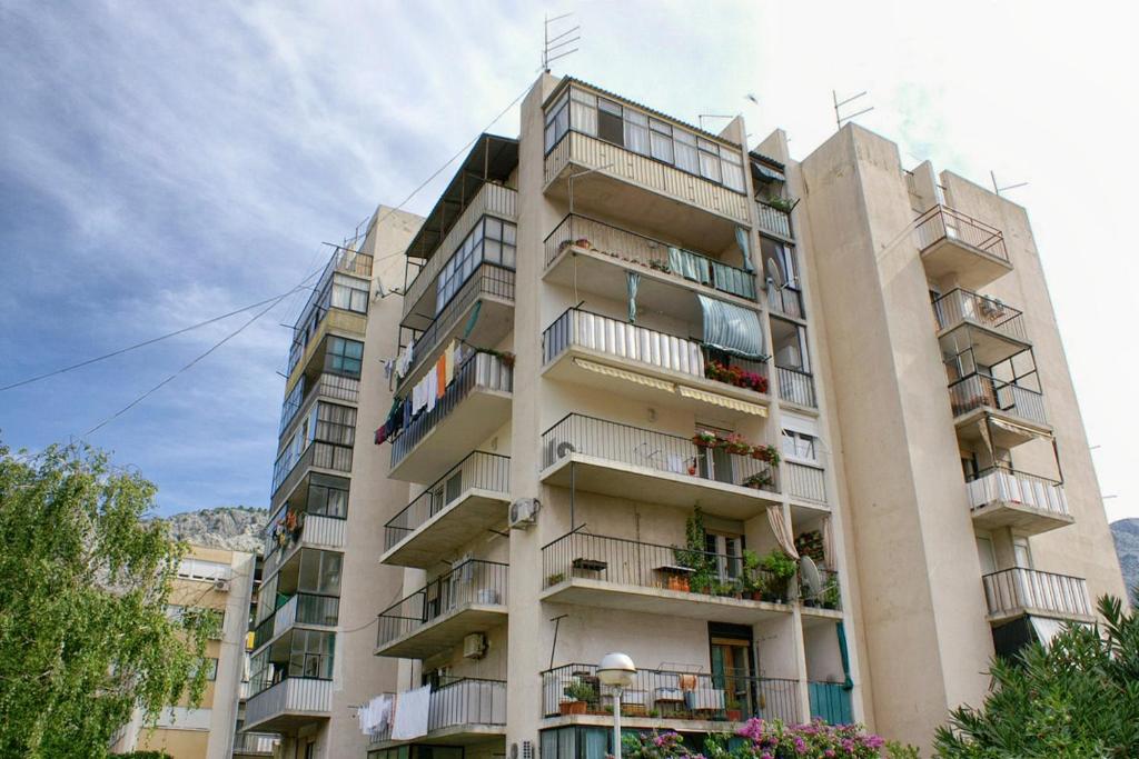 a tall apartment building with balconies on it at Apartments by the sea Omis - 13796 in Omiš