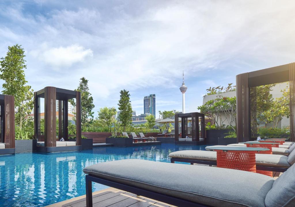 - une piscine avec des chaises longues et des tables dans un bâtiment dans l'établissement PARKROYAL COLLECTION Kuala Lumpur, à Kuala Lumpur