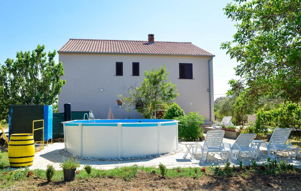 a backyard with a pool and chairs and a house at Apartments with swimming pool Poljica, Zadar - 13838 in Vrsi