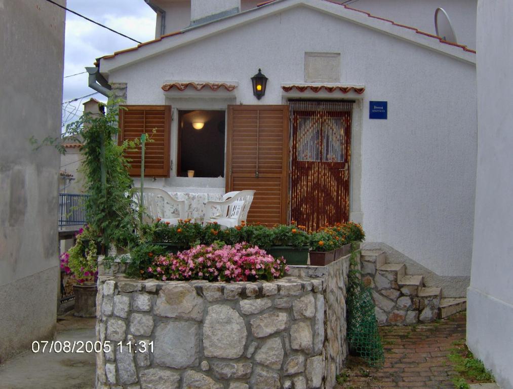 a white house with a stone wall and flowers at Secluded house with a parking space Beli, Cres - 13893 in Beli