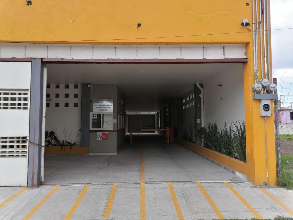 Zugang zu einem Parkhaus mit einem gelben Gebäude in der Unterkunft Hotel Santino in Toluca de Lerdo
