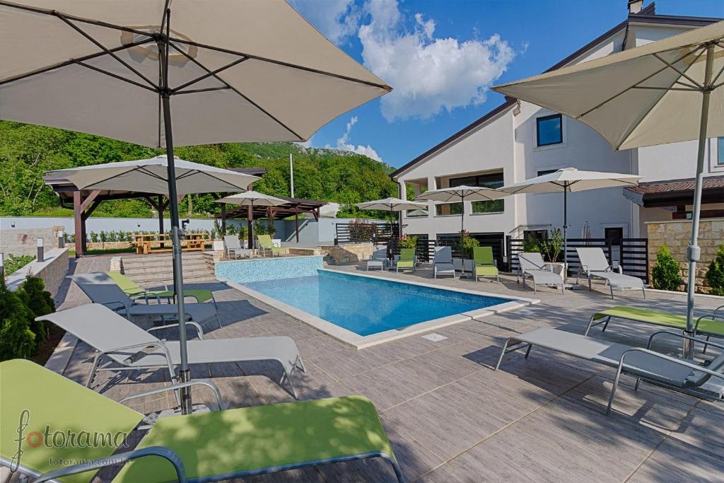 ein Pool mit Stühlen und Sonnenschirmen neben einem Gebäude in der Unterkunft Luxury villa with a swimming pool Dolinci, Crikvenica - 13914 in Grižane